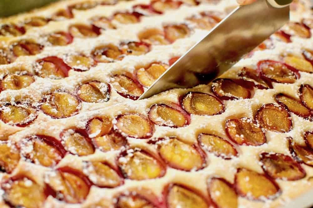 Cutting a slice of vegan plum cake