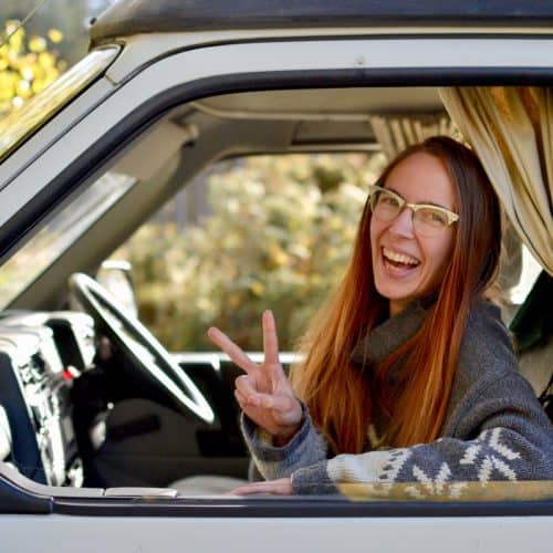 Sophie laughs in the passenger seat of a campervan