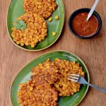 Crispy, yellow corn fritters on two green plates