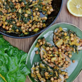 A pan with stirfried chickpeas and chard, next to a plate with three slices of toast