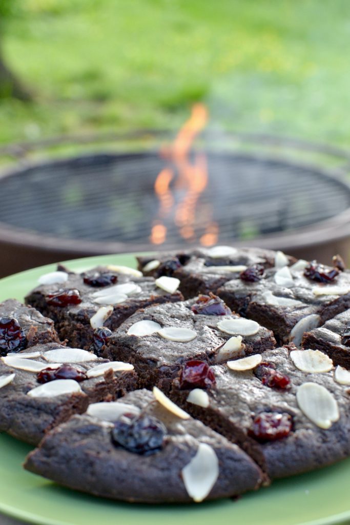 A plateful of vegan brownie in front of a campfire