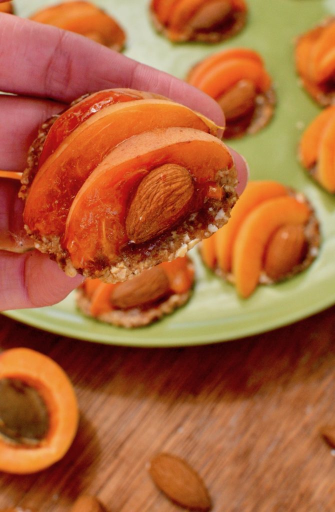 A detail of a mini tart showing how an almond nestles in a slice of apricot, just like an apricot stone.