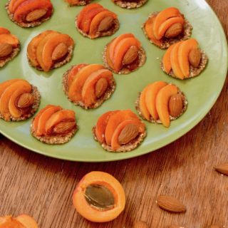 A green plate coverd in mimi apricot and almond topped no bake tarts