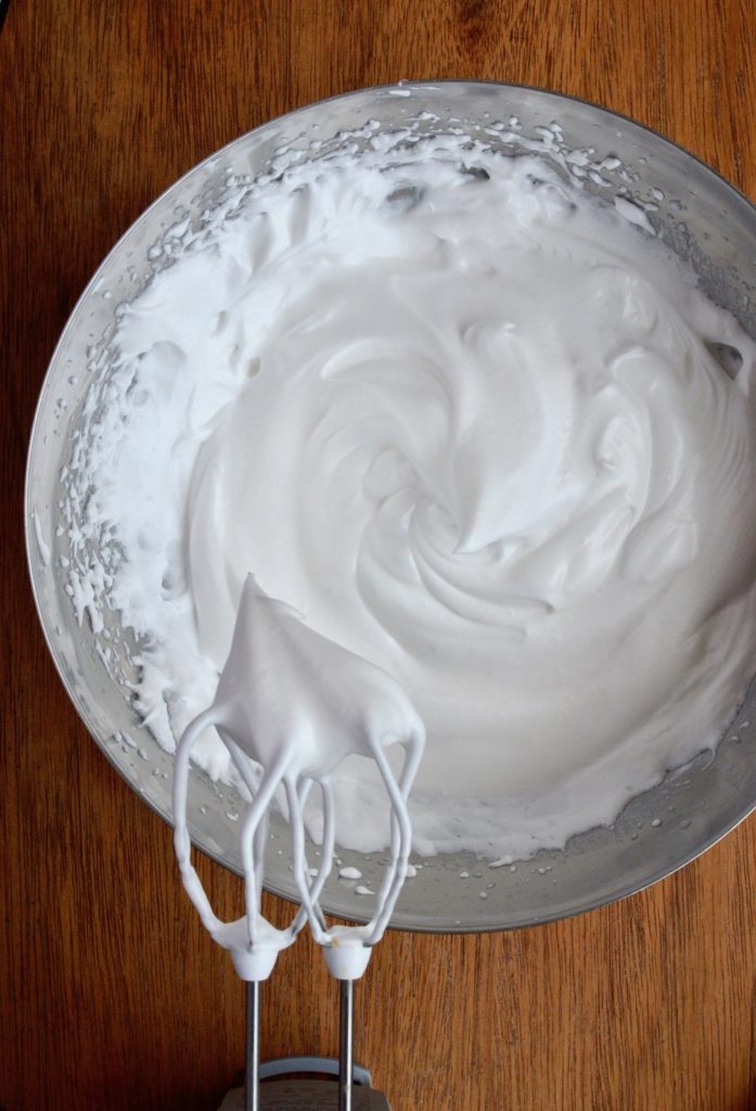 Aquafaba meringue holding stiff peaks from the beathers of an electric whisk