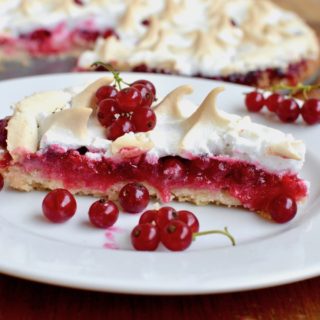 A slice of tart with a pink reducrrant filling and vegan meringue topping