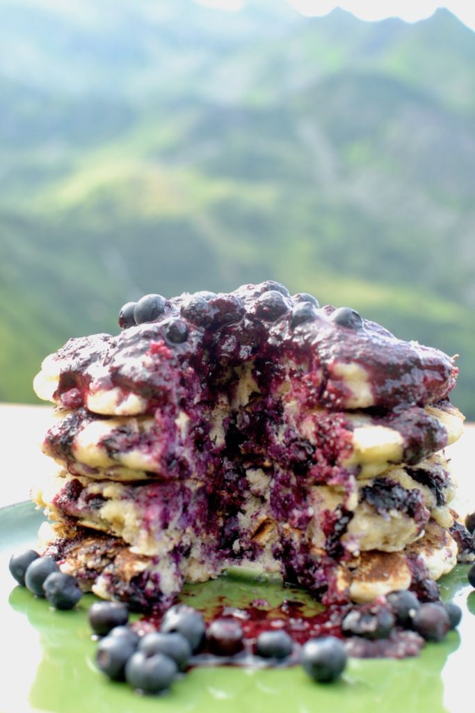 A stack of pancakes with a slice taken out so you can see the inside filled with berries