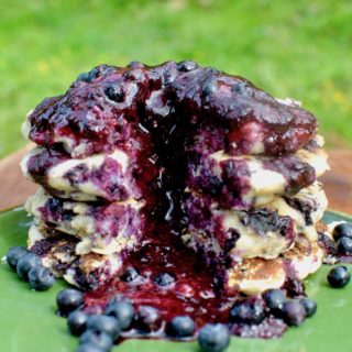 A stack of blueberry pancakes covered in dark purple berry sauce