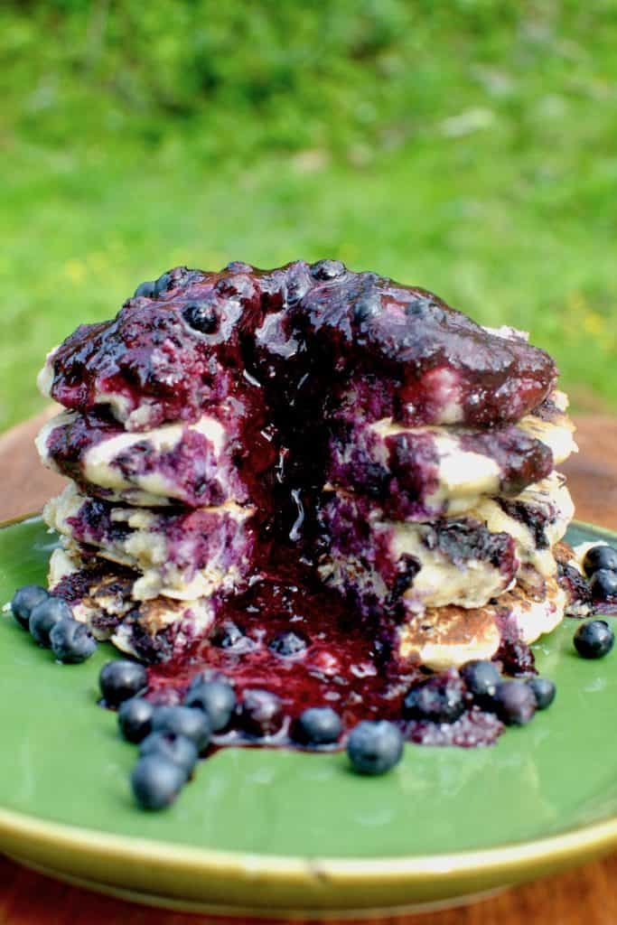 A rich red purple berry sauce flows down the pancake stack