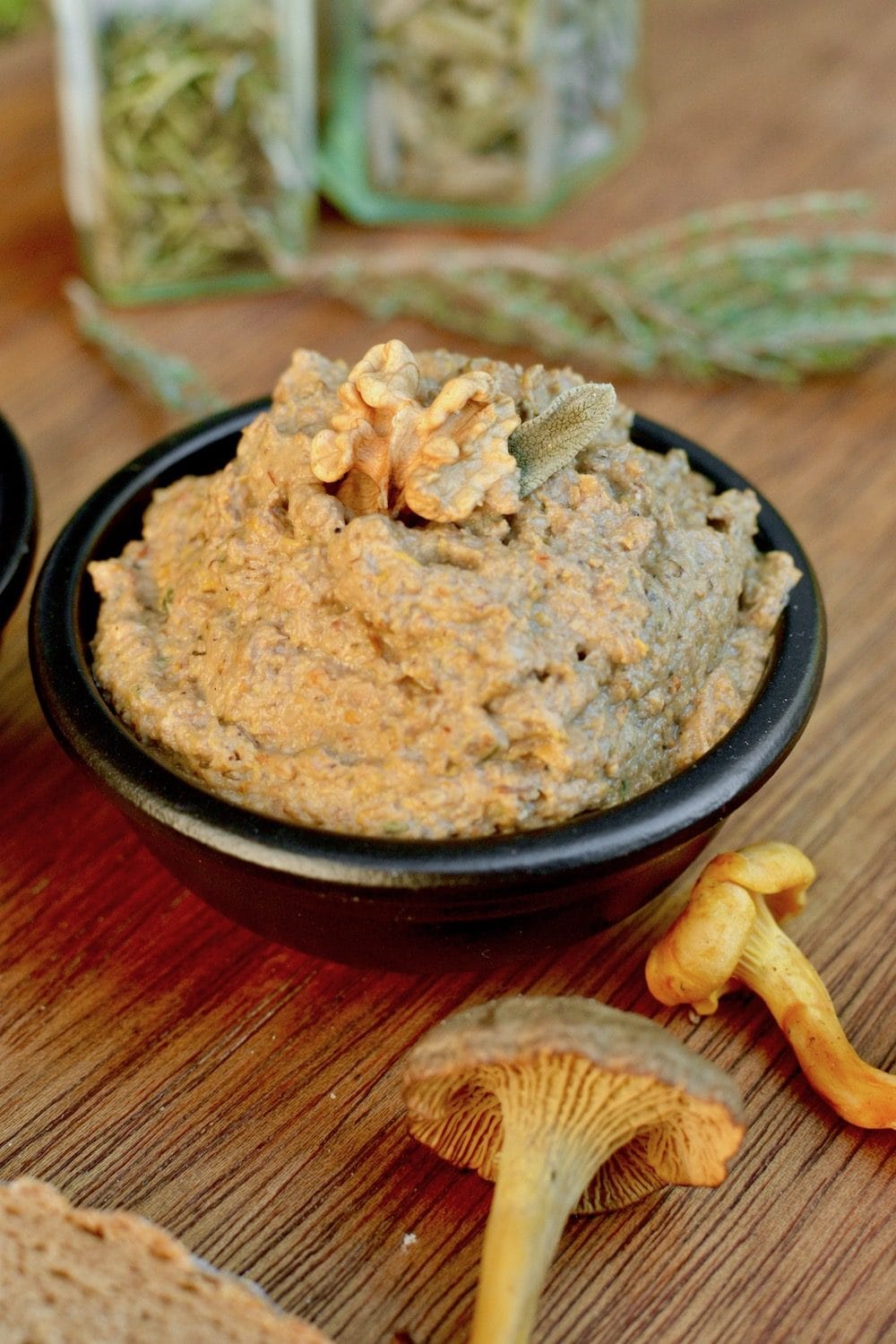 A pot of vegan mushroom pate, with a walnut and sage leaf on top