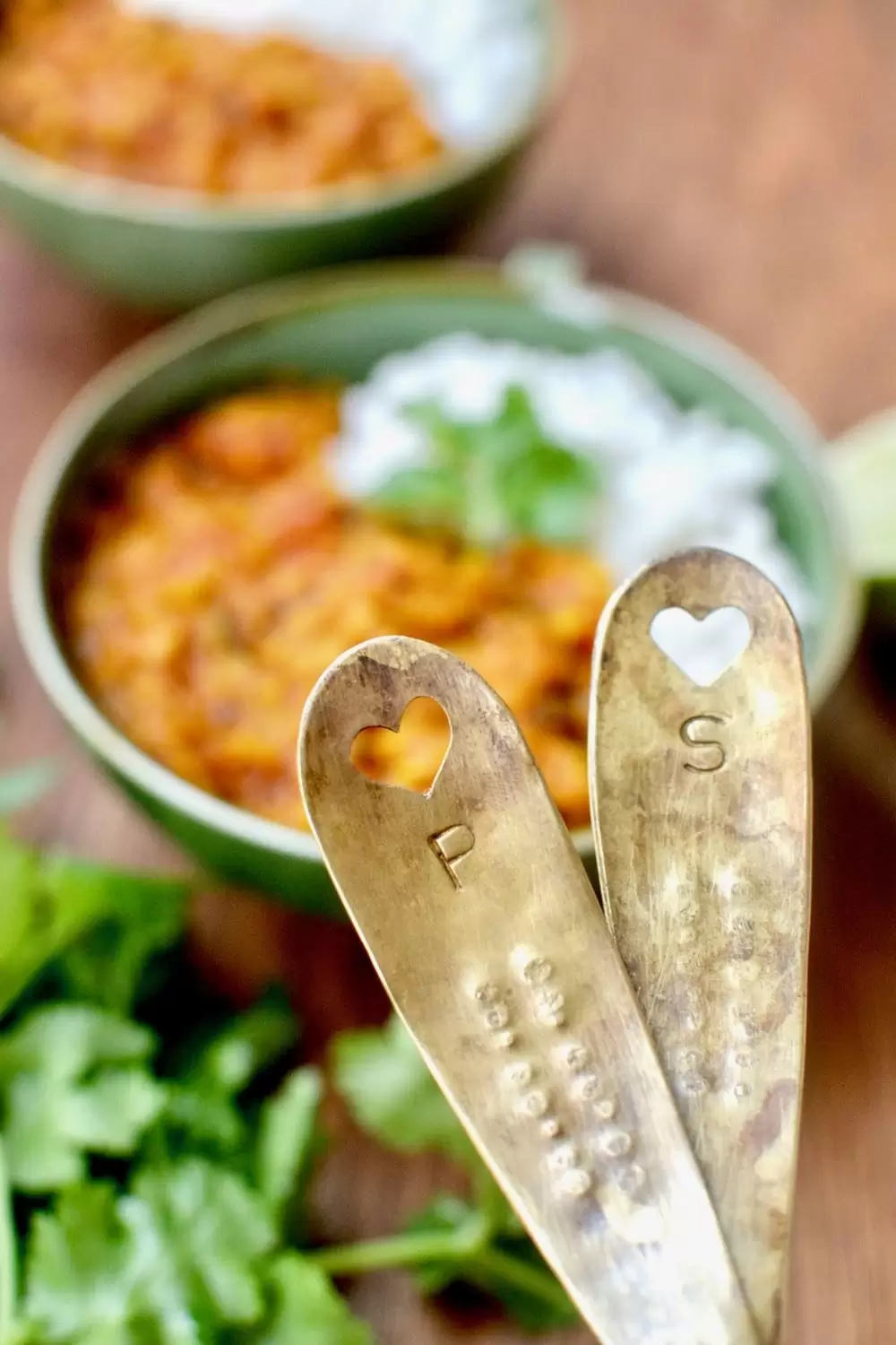 Two personalised spoons with heart cutouts, in the background you can see the Red Lentil Dal of Love