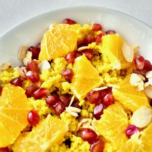 Sunshine yellow couscous topped with oranges, pomegranite and nuts