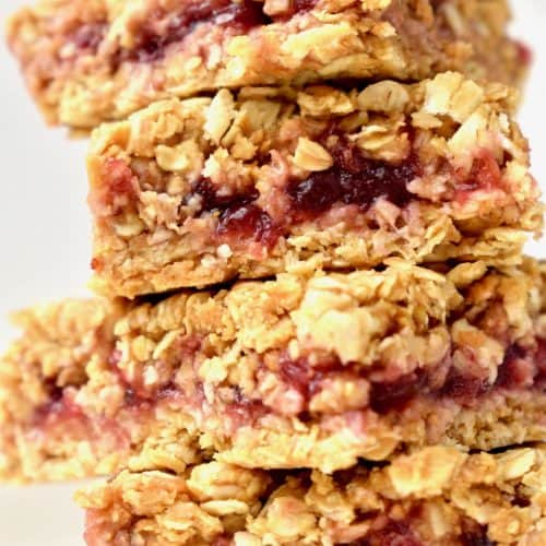A stack of four red jam filled peanut butter oat bars