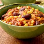 Cooked beans, sweetcorn, fried herbs and a tomato and soy mince sauce in a bowl