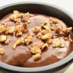 The shiny, brown surface of the pudding, topped with caramelised hazelnuts