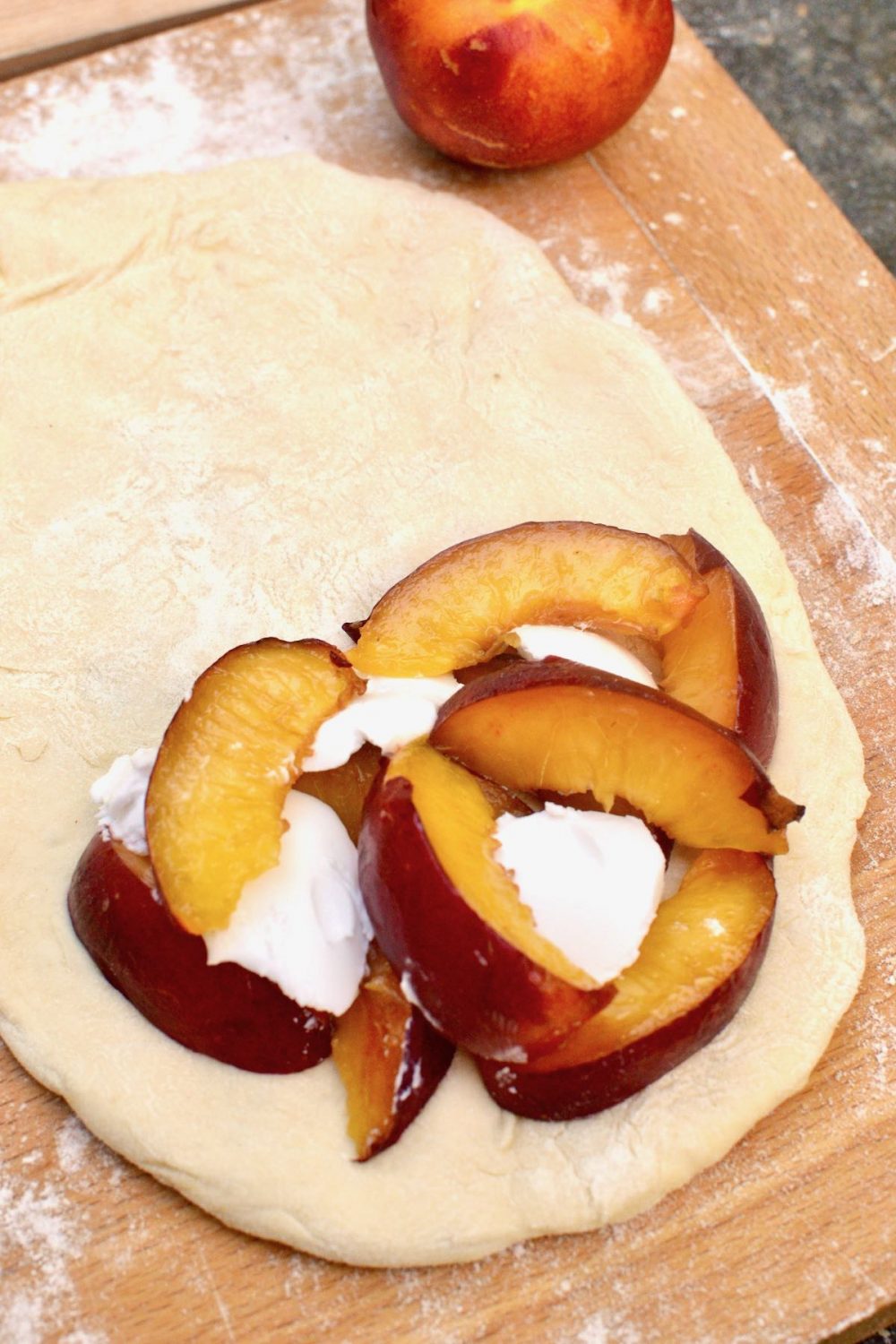 Fresh peach slices and coconut cream are used as a filling for a piece of dough.