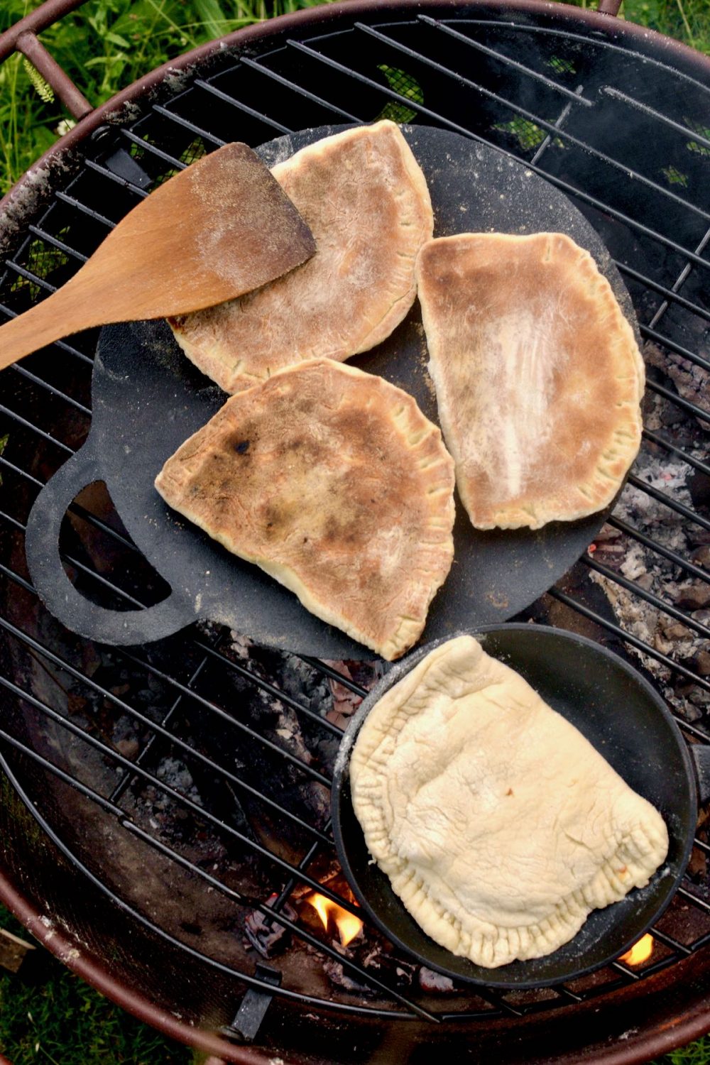 Three calzone have been turned over on the cooking stone and show a brown crunchy crust.
