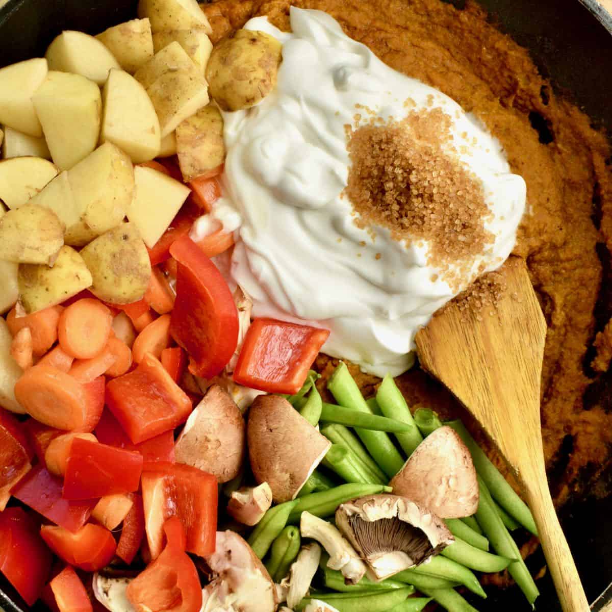Adding the vegetables, coconut yoghurt and sugar to the korma paste.