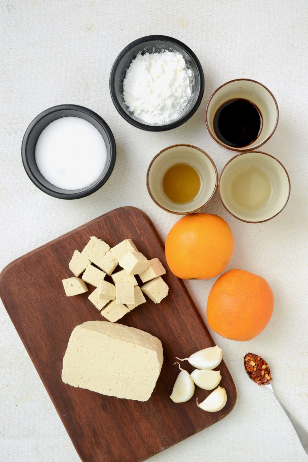 The ingredients that you will need if you want to make this recipe for orange tofu: A block of firm tofu, two medium oranges, garlic, sesame oil, soy sauce, rice vinegar, sugar and cornstarch. Chili flakes are an optional addition.