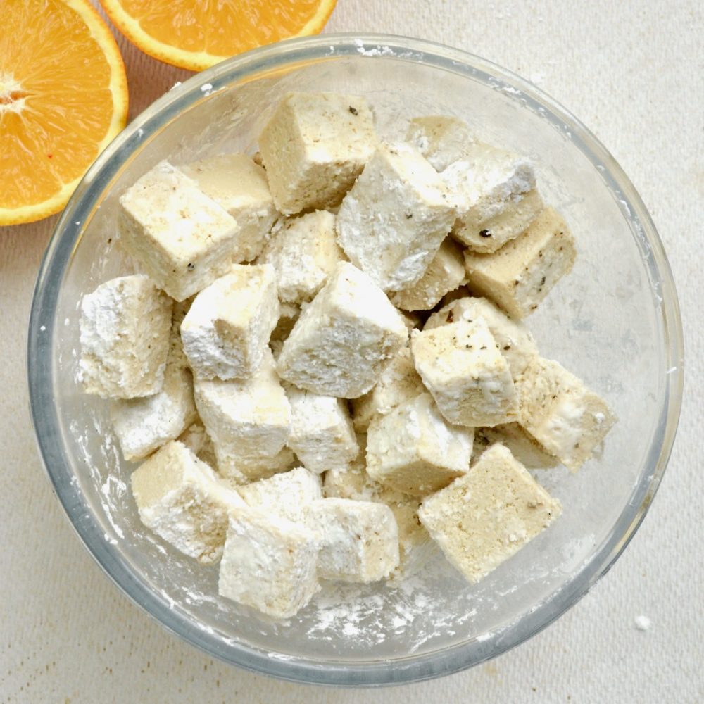 A bowlful of tofu cubes evenly coated with cornstarch.