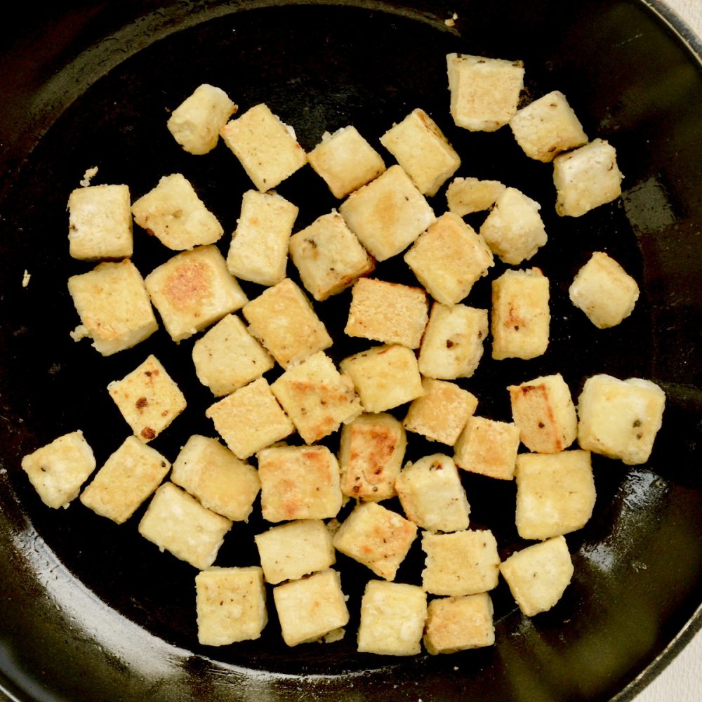 The coated tofu cubes are fried until golden brown and slightly crisp.