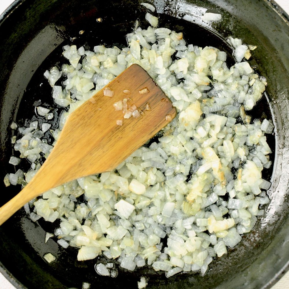 Finely diced onions sauteeing in a frying pan.