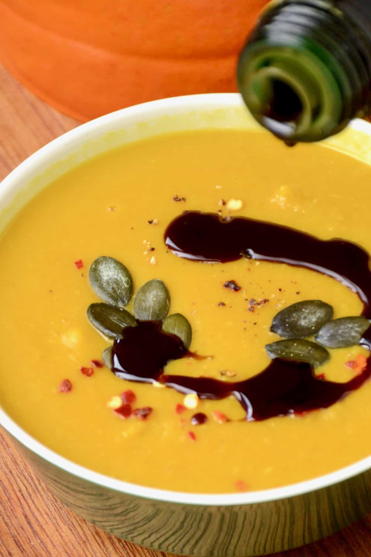 A drizzle of dark pumpkin seed oil poured on top of the soup.