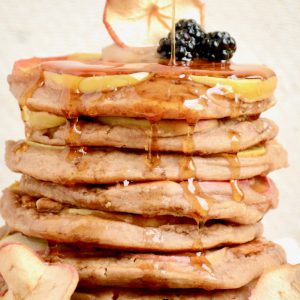Golden maple syrup falls down the sides of the pancakes.