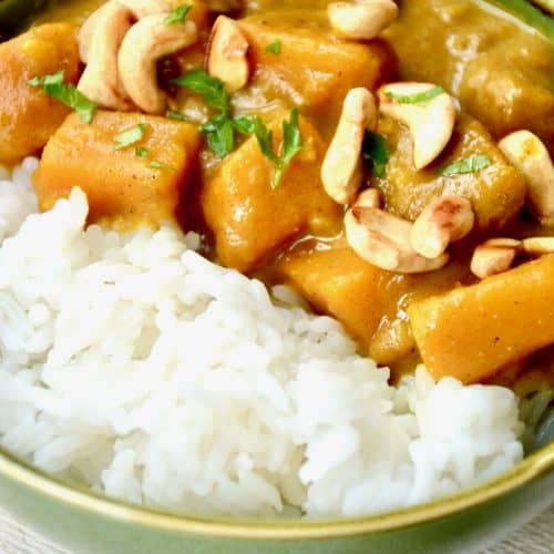 Cubes of pumpkin in a thick curry sauce, topped with cashews and served with white rice.