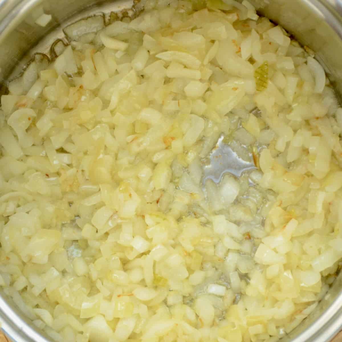 Diced onions stating to brown in a saucepan.