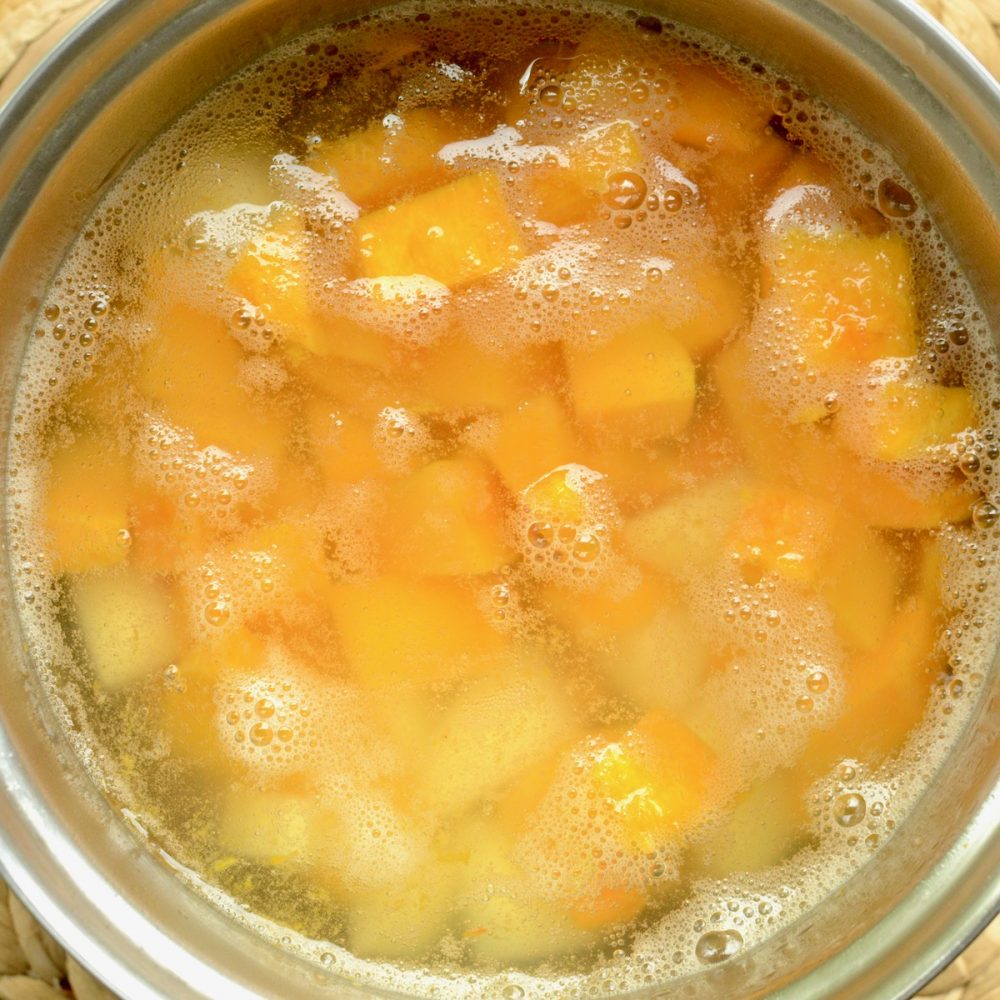 Cubes of pumpkin and potato cooking in a saucepan.