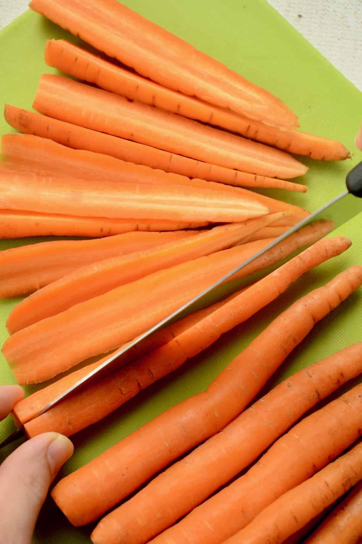 Carrots being chopped in half lengthwise.