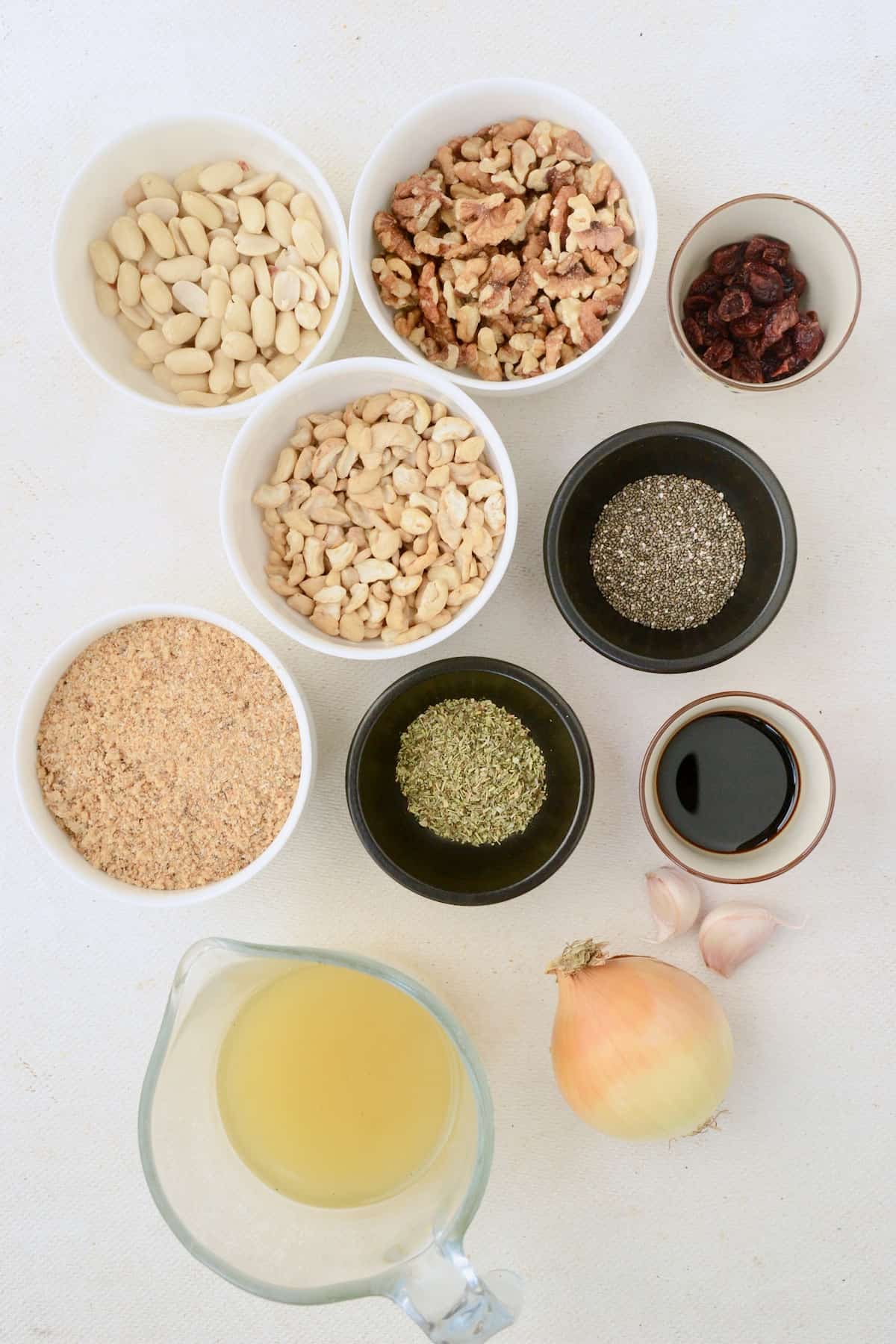 The ingredients for the nutroast recipe: Different types of nuts, breadcrumbs, an onion, some garlic, dried herbs, vegetable bouillon, soy sauce, chia seeds and dried cranberries.
