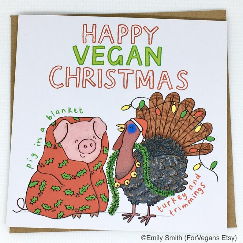 A gift card reading 'Happy vegan Christmas'. The drawn illustration shows a smiling pig wrapped in a warm blanket and a live turkey covered in christmas decorations. The drawings are labeled 'pig in a blanket' and 'turkey and trimmings'.