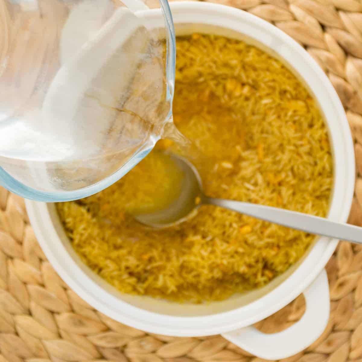 A jug pours boiling water onto the spiced rice.