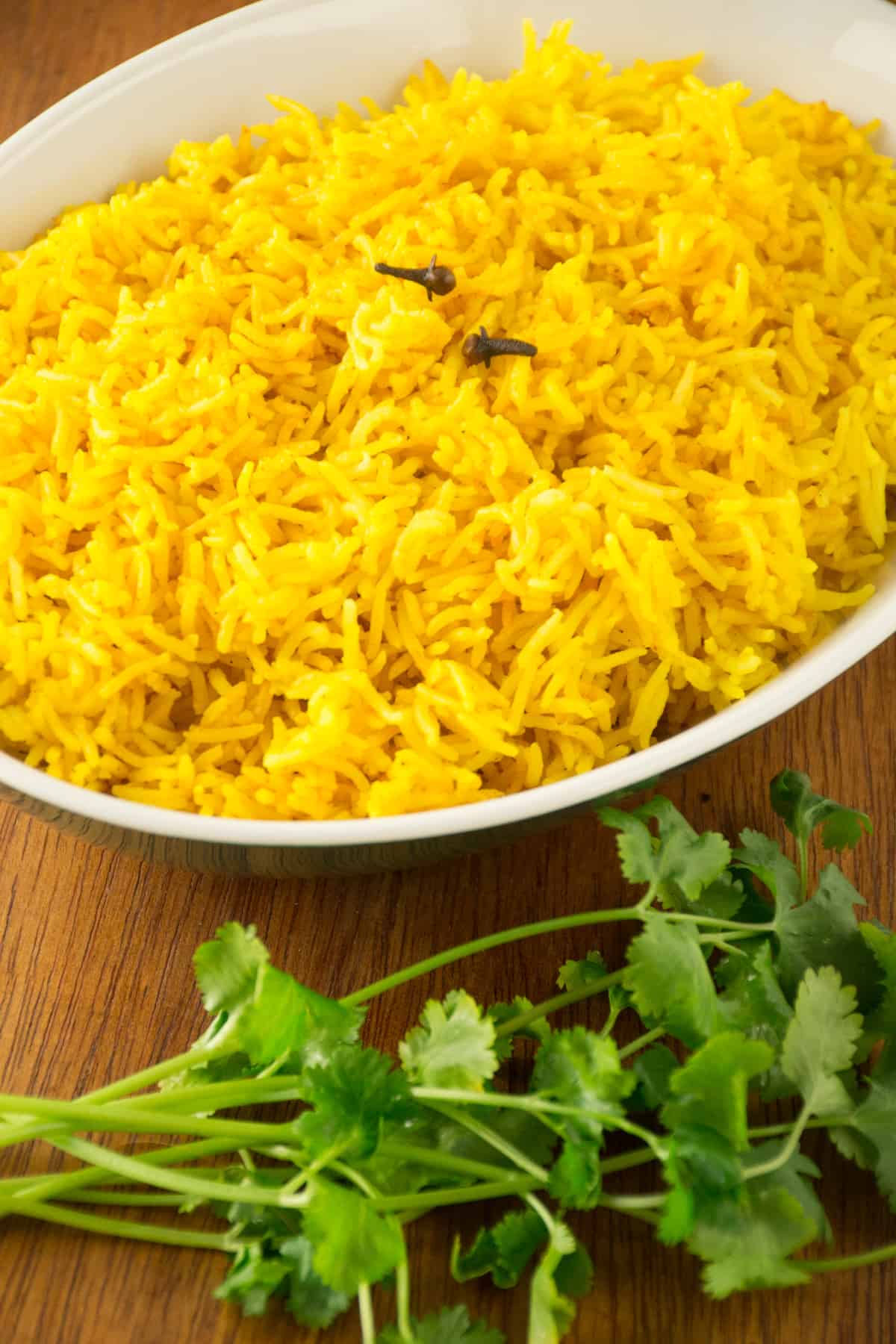 A dish of turmeric rice, with two whole cloves on top.