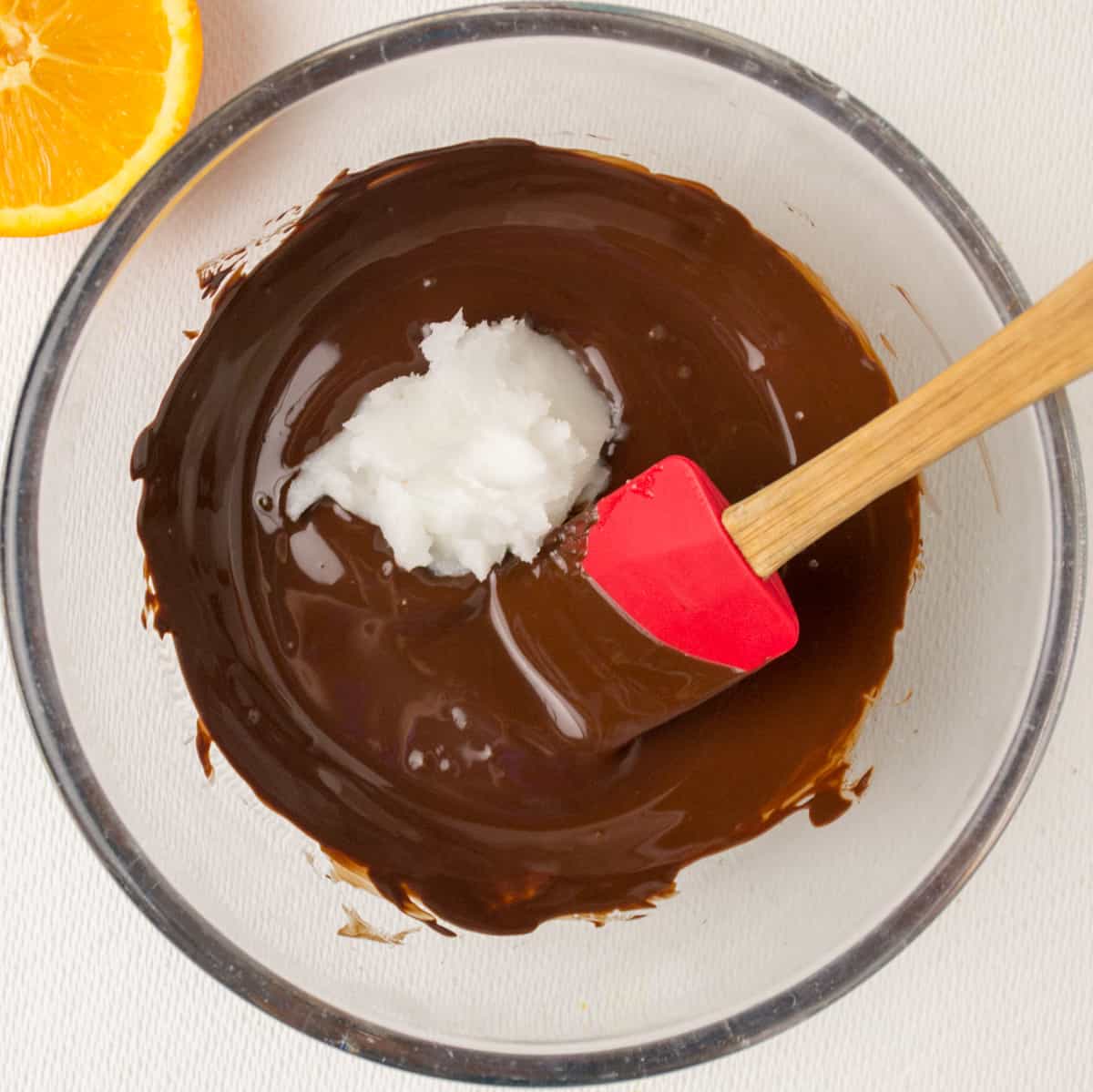 Adding coconut oil to the melted chocolate.