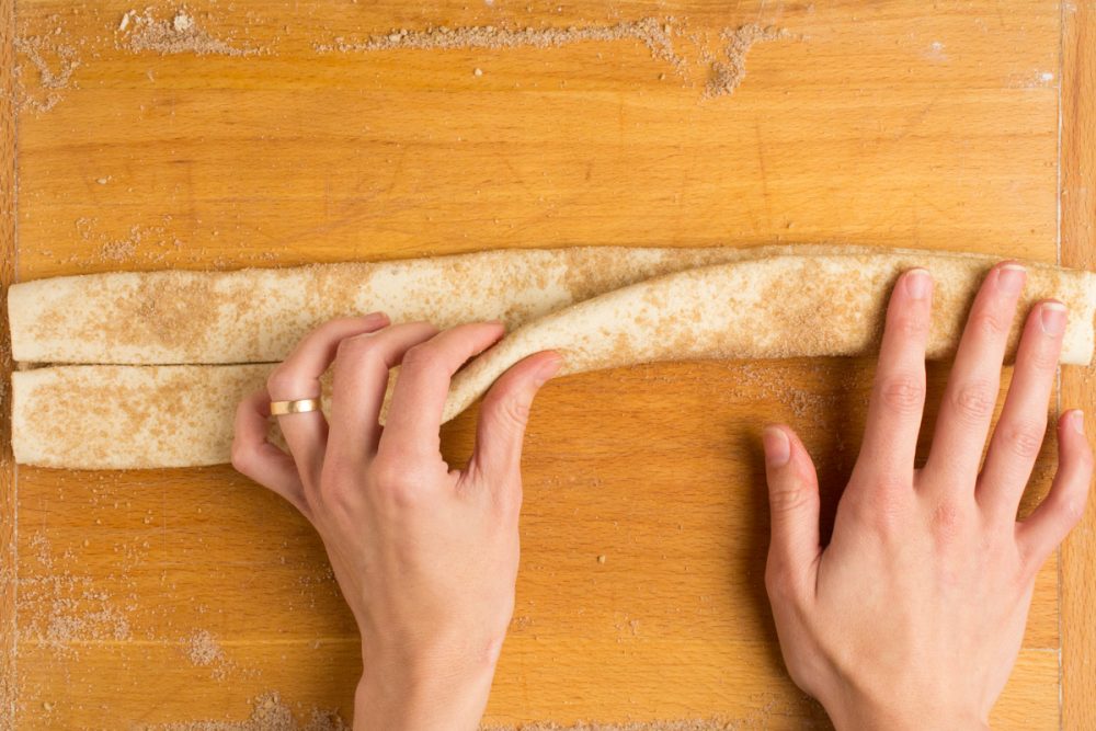 A hand folds the bottom over the top to make a long strip.