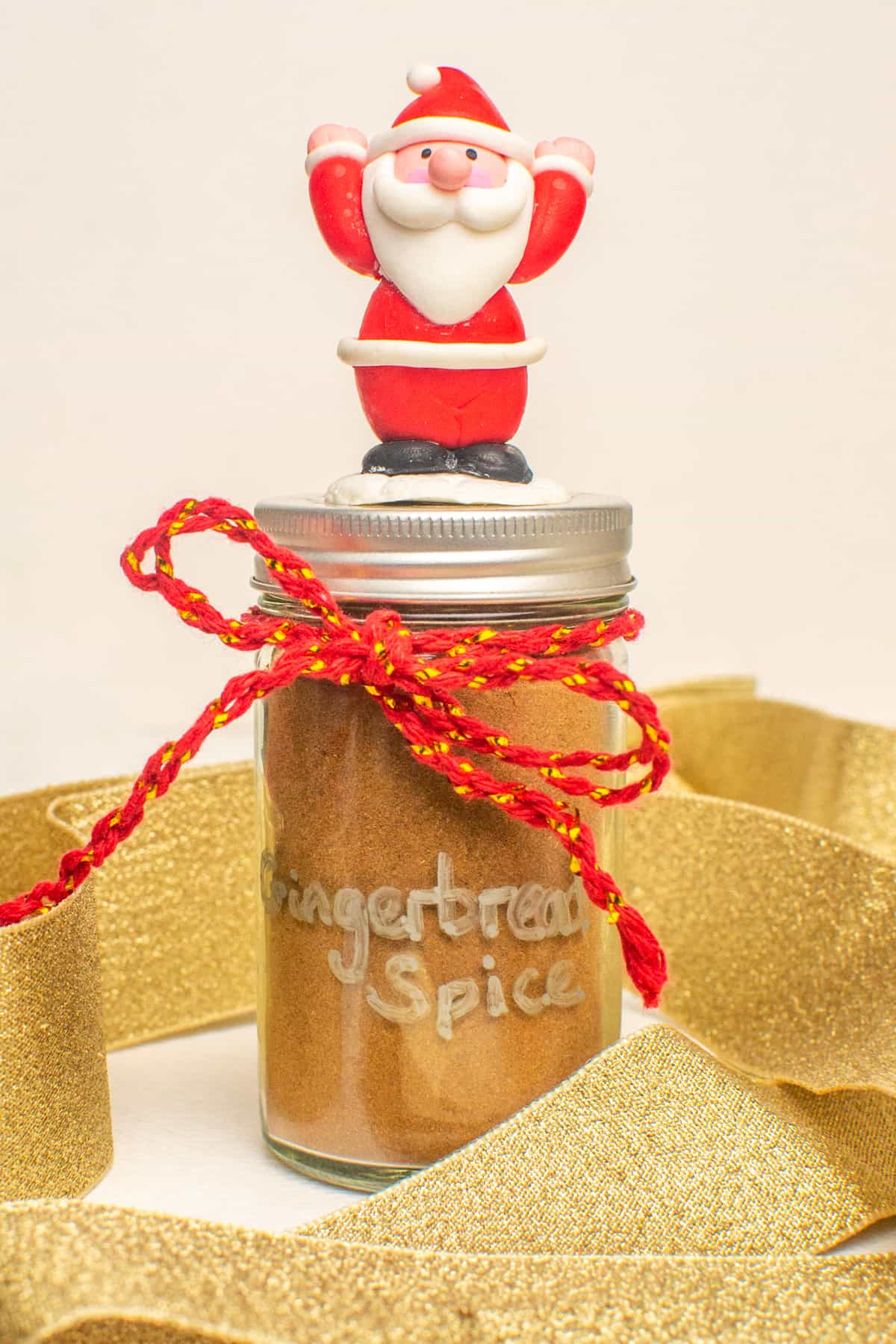 A jar of spice decorated with ribbon, twine and a small Father Christmas on top.