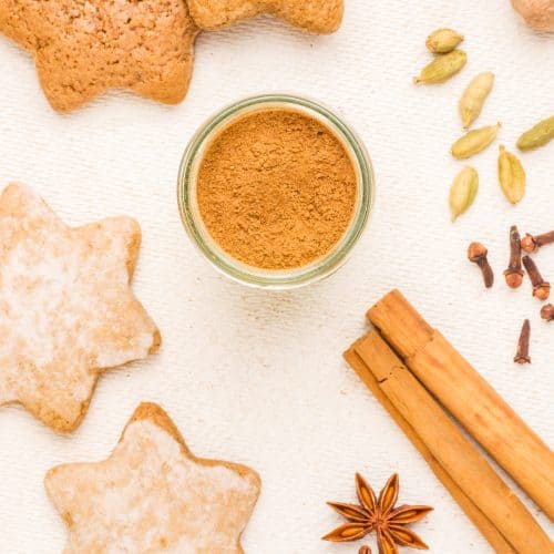 Seen from above, gingerbread spices in the centre surround by star shaped cookies and whole spices.
