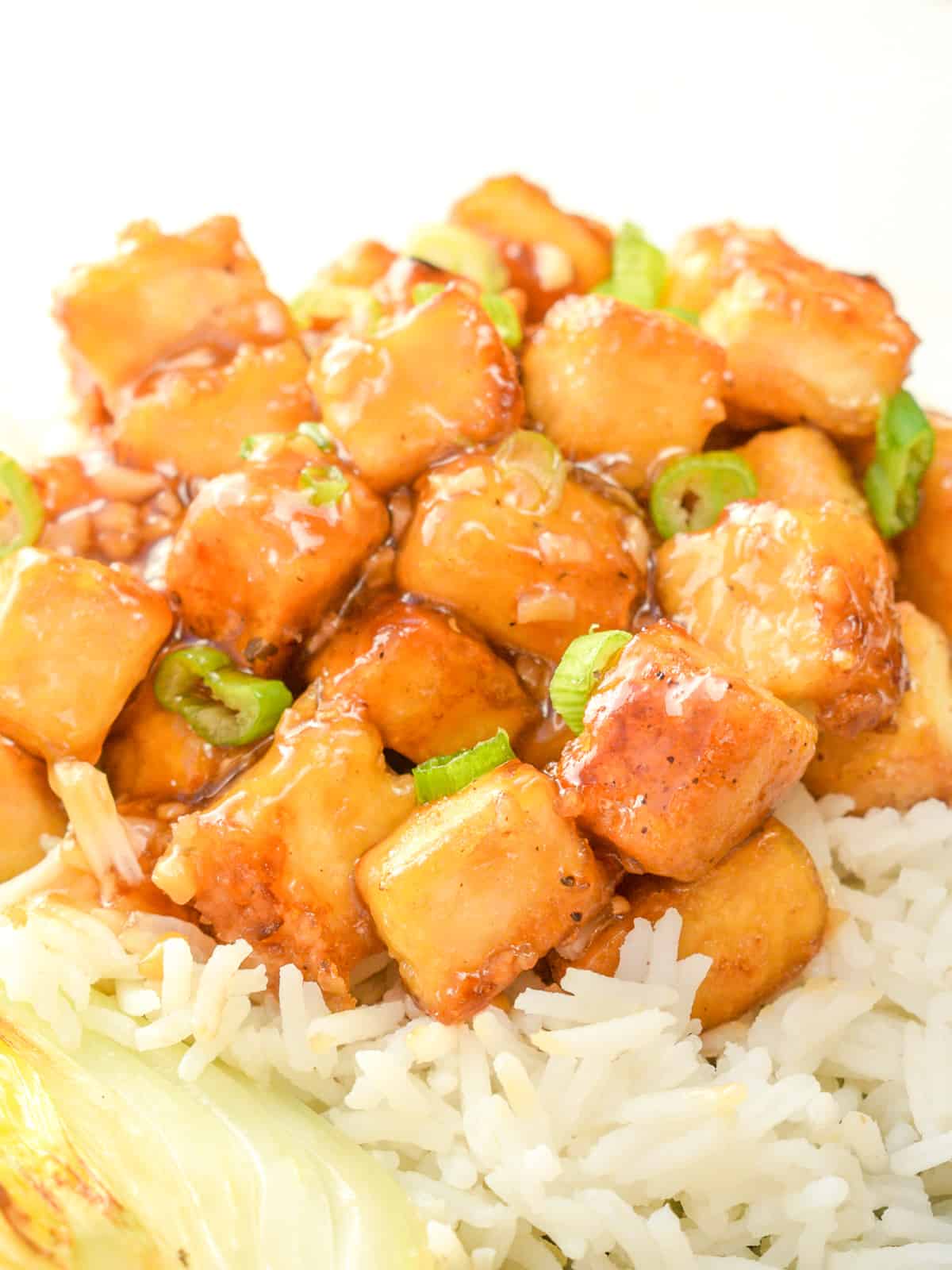 Cubes of tofu covered in a stickey lemon sauce on white rice.