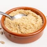 A spoon scoops a portion of vegan parmesan cheese.