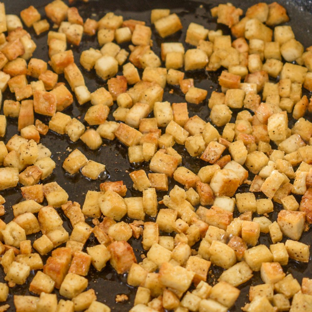 Cubes of smoked tofu frying in olive oil.