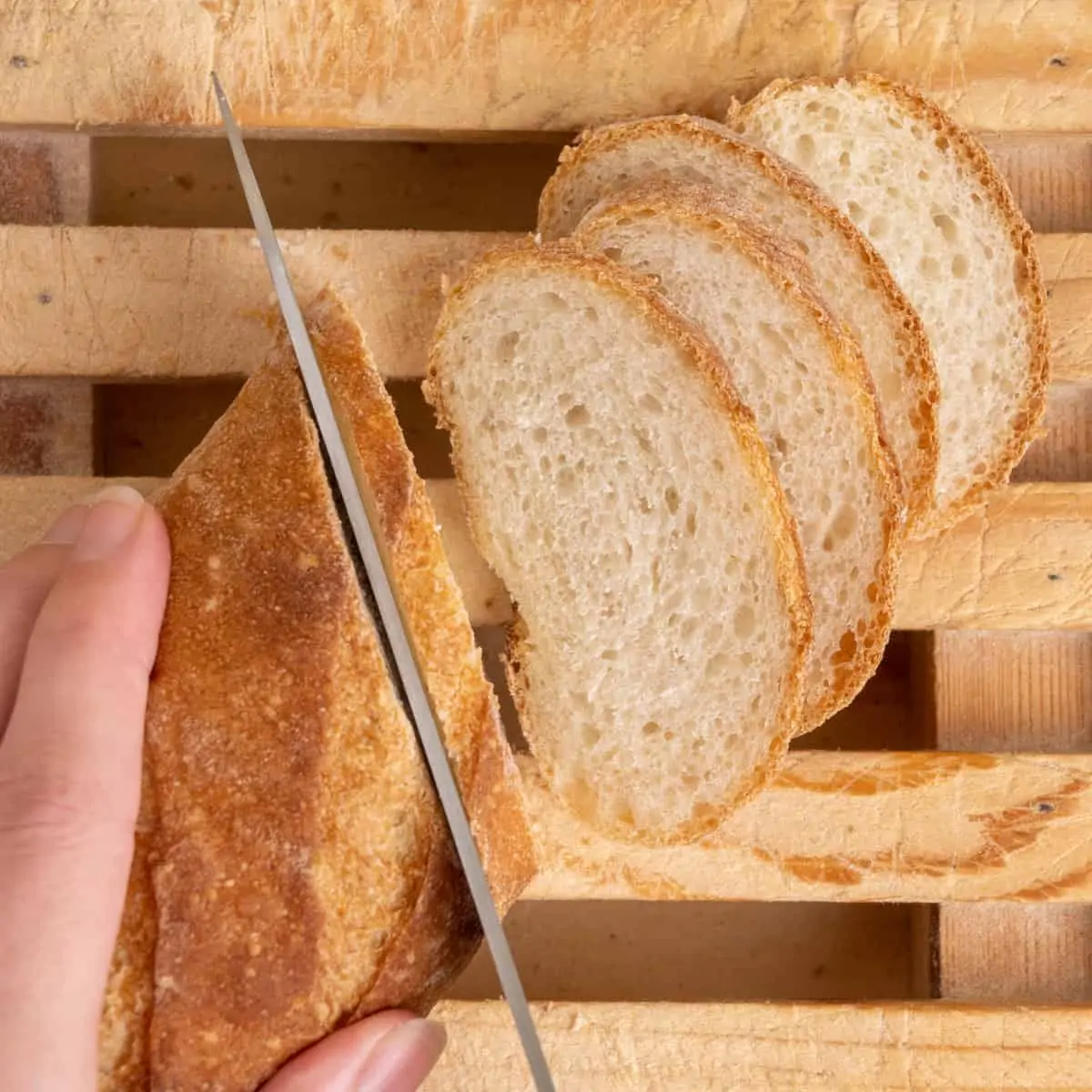 A baguette is sliced into thin diagonal slices.