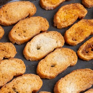Crostini on the tray after baking. They are golden brown and appear crispy.