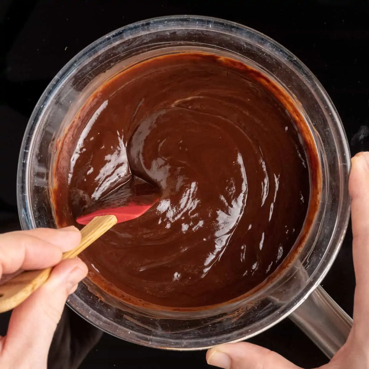 Stirring the melted chocolate mixture until smooth and thick.