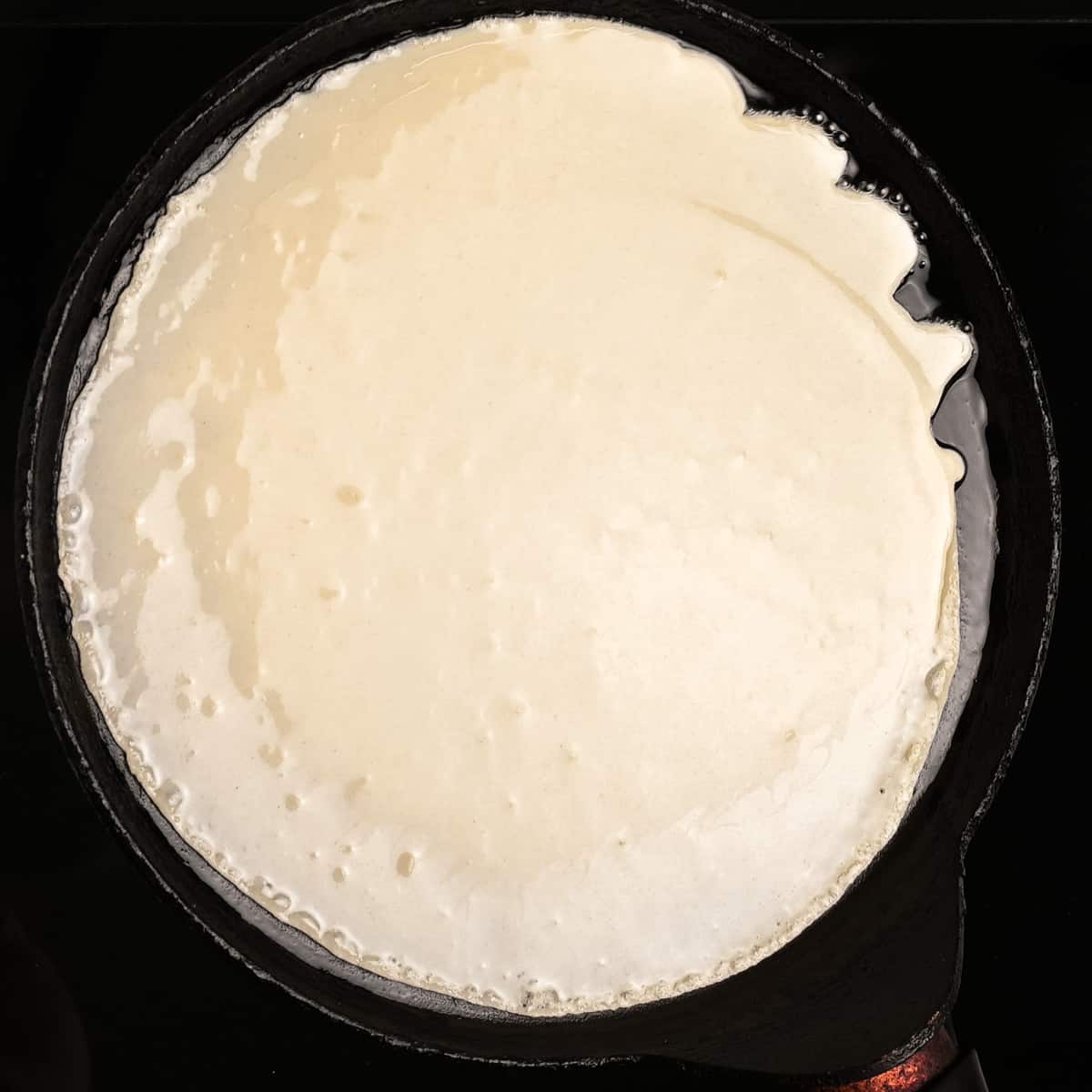Tilting the pancake pan to spread out the batter.