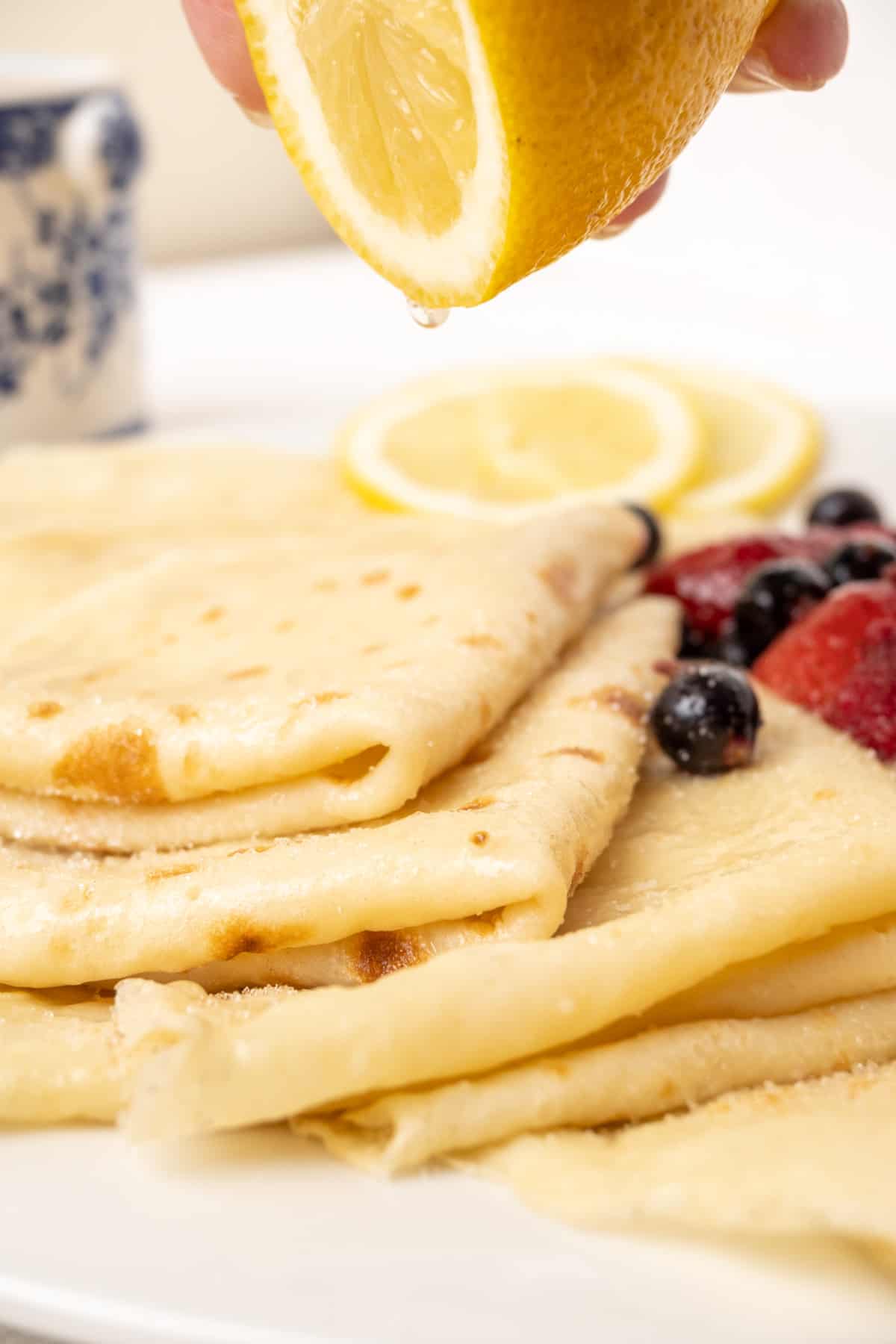 Squeezing lemon onto a pile of thin pancakes.