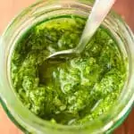 Looking down into a jar of bright green pesto.