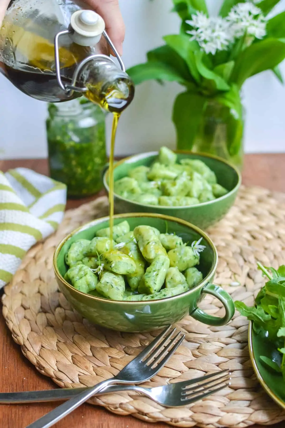 Drizzling olive oil over the gnocchi.