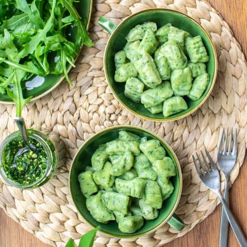 Two green bowls with green gnocchi in. Salad and wild garlic pesto on the side.